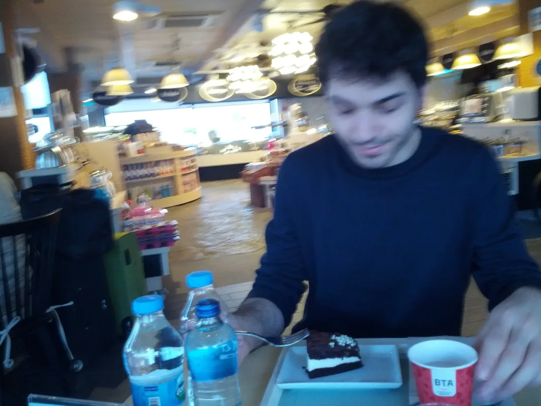 Emre-E. Yavuz at a café table with a slice of cake.